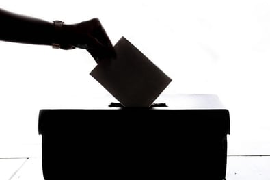 a voting ballot going into a box